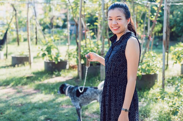 Азиатская молодая женщина с собакой гуляет в саду на заднем дворе дома утром