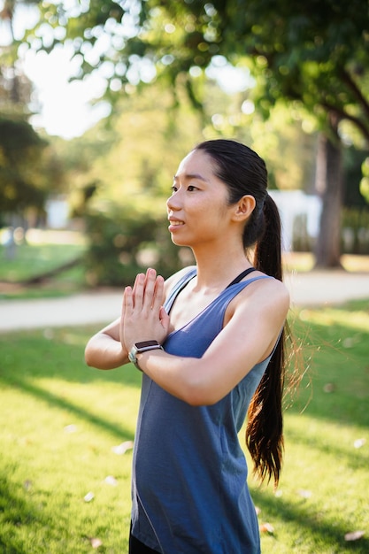 Asian young woman doing yoga exercises outdoors in the park