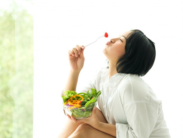 Photo asian young woman eatiing salad on white background diet food