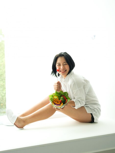 Photo asian young woman eatiing salad on white background diet food