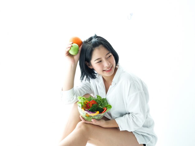 Photo asian young woman eatiing salad on white background diet food