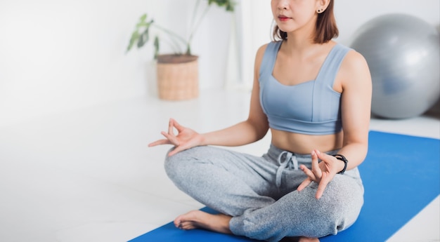 Asian young woman exercise and play yoga meditation at home background.Concept of Exercise during the quarantine at home for preventing coronavirus and covid-19 infection.