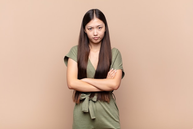 Asian young woman feeling displeased and disappointed, looking serious, annoyed and angry with crossed arms