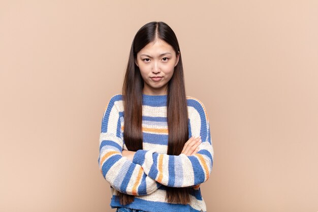 Asian young woman feeling displeased and disappointed, looking serious, annoyed and angry with crossed arms