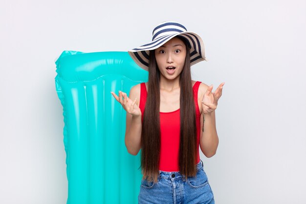 Asian young woman feeling extremely shocked and surprised, anxious and panicking, with a stressed and horrified look. summer concept