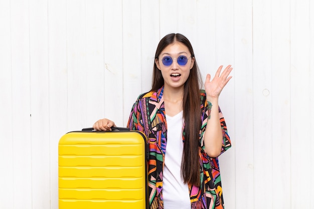 Asian young woman feeling happy, amazed, lucky and surprised, celebrating victory with both hands up in the air. holidays concept