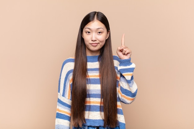 Asian young woman feeling like a genius holding finger proudly up in the air