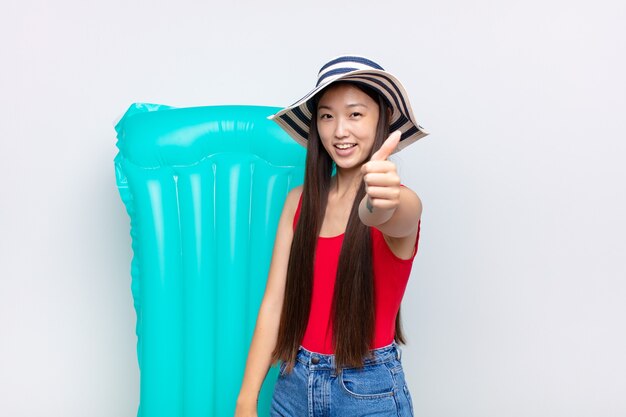 Asian young woman feeling proud, carefree, confident and happy, smiling positively with thumbs up