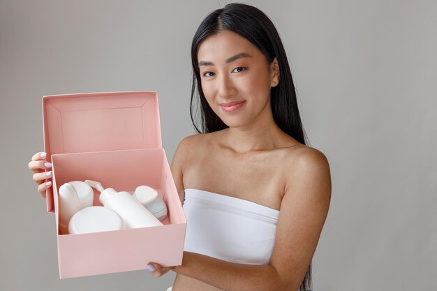 Asian young woman holding box with cosmetic products