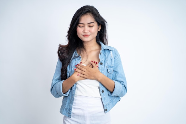 Asian young woman holding chest while feeling relieved