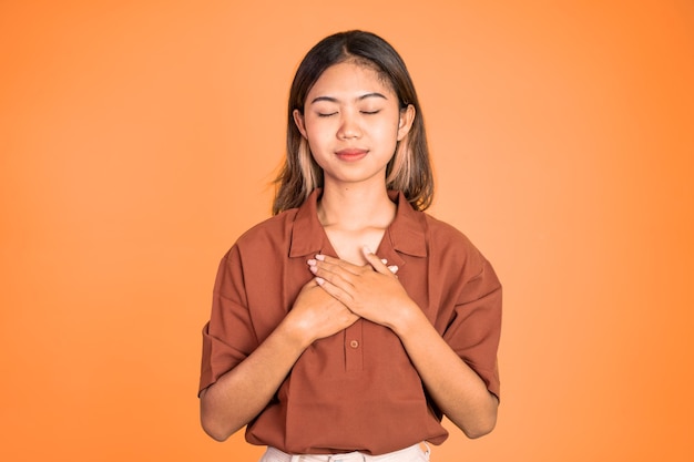 Asian young woman holding chest while feeling relieved