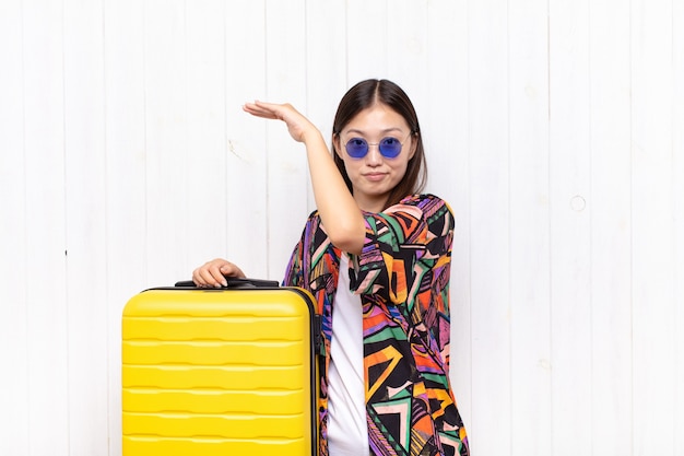 asian young woman holding an object with both hands on side copy space, showing, offering or advertising an object. holidays concept