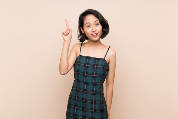 Asian young woman over isolated yellow wall intending to realizes the solution while lifting a finger up