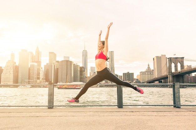 Азиатская молодая женщина прыгает с горизонтом Нью-Йорка