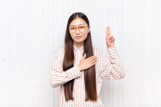 Asian young woman looking happy, confident and trustworthy isolated