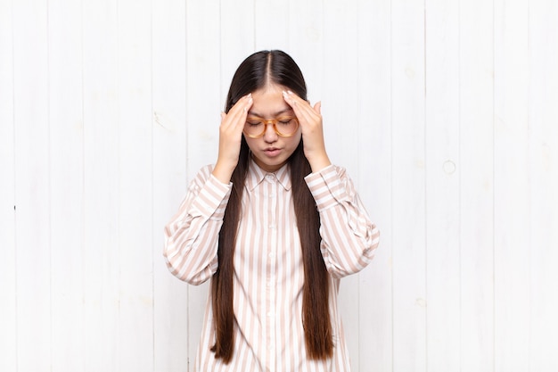 Asian young woman looking stressed and frustrated, working under pressure with a headache and troubled with problems