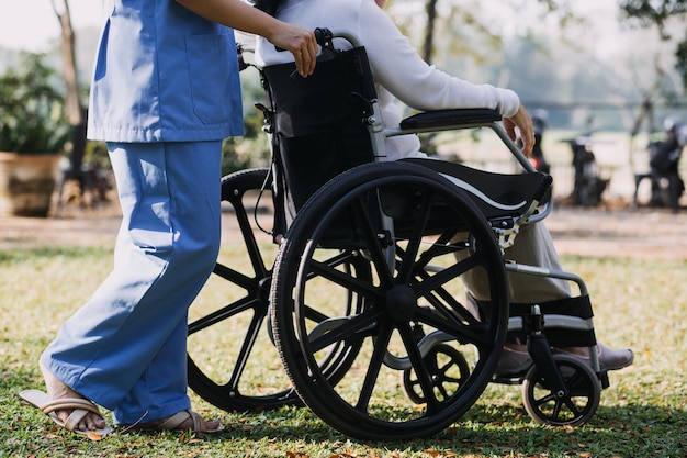 Asian young woman nurse at nursing home take care disabled senior man Caregiver doctor serve physical therapy for older elderly patient to exercise and practice walking on walker or cane at backyard