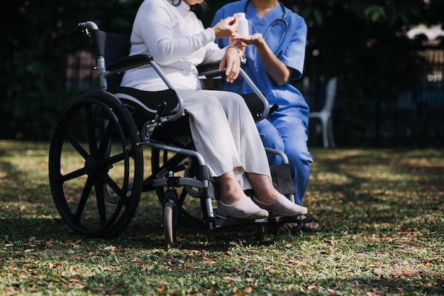 Азиатская молодая женщина-медсестра в доме престарелых заботится о пожилом человеке-инвалиде Врач-опекун оказывает физиотерапию пожилому пациенту, чтобы он мог тренироваться и практиковаться в ходьбе на ходунках или трости на заднем дворе