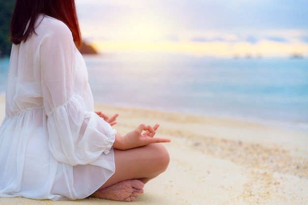 Photo asian young woman practice yoga on the beach near the sea under sunlight at sunrise, relaxation for health in the midst of nature with happiness and peace, blank for the background