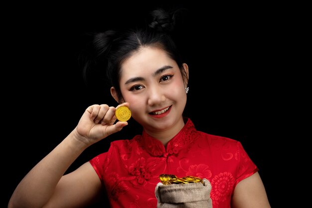 写真 袋に金貨を持っているアジアの若い女性の赤いドレス伝統的なチャイナドレス