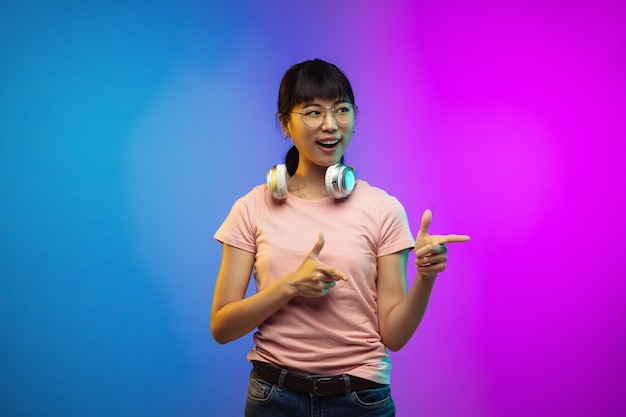 Asian young woman's portrait on gradient studio background in neon