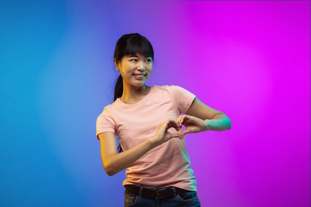 Asian young woman's portrait on gradient studio background in neon