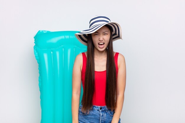 Asian young woman shouting aggressively, looking very angry isolated