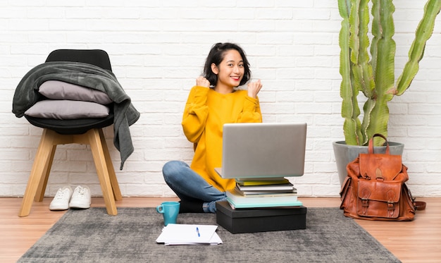 Asian young woman sitting on the floor celebrating a victory