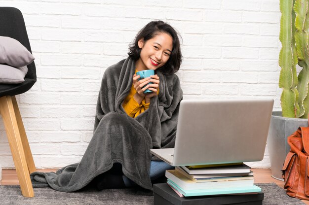 Asian young woman sitting on the floor holding a cup of coffee