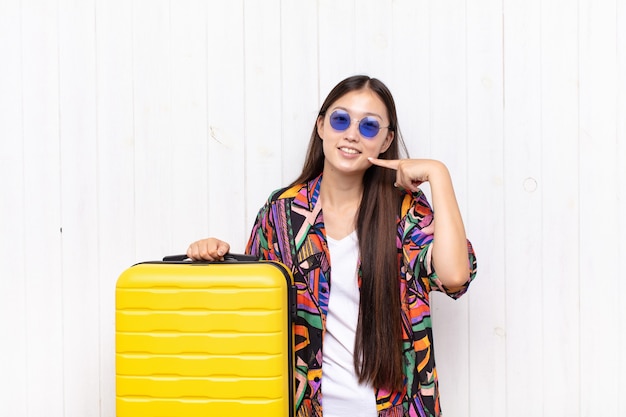 Asian young woman smiling confidently pointing to own broad smile