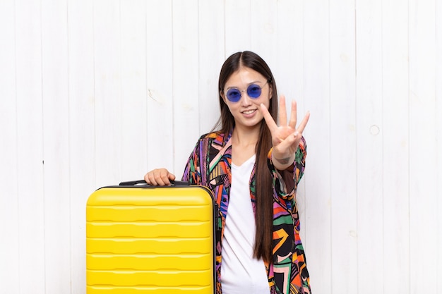 Asian young woman smiling and looking friendly, showing number four or fourth with hand forward, counting down. holidays concept