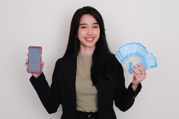 Asian young woman smiling while holding money and blank mobile phone screen