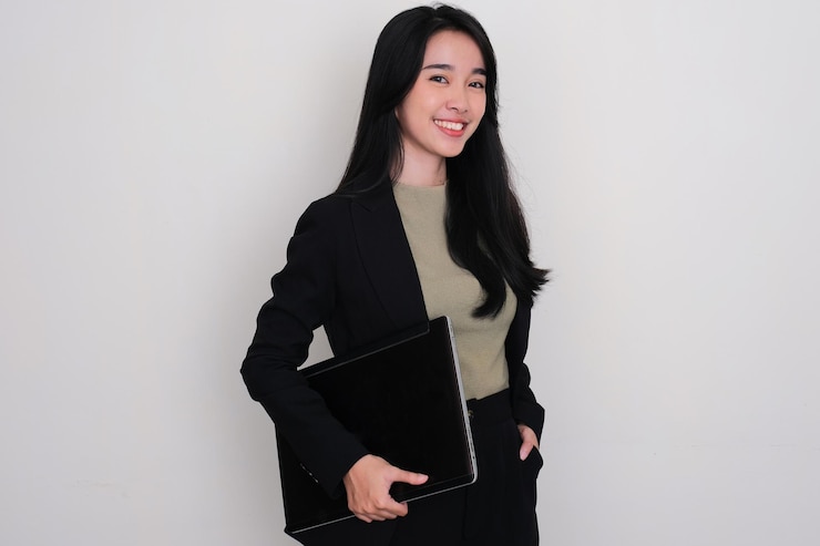 Photo 一位亞洲年輕女人站著,拿著筆記型電腦微笑
