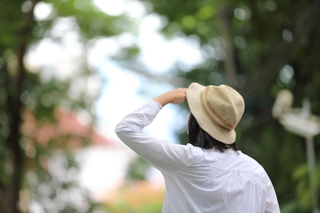 緑の木の背景と旅行の概念の肖像画を考えて探しているアジアの若い女性