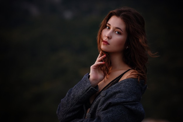 Asian young woman tourist wearing coat in view of mountain against fall forest Girl in underwear wrapped in a gray coat