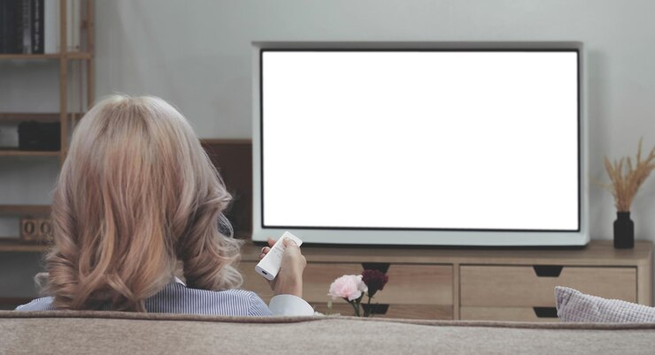 Photo 自宅のソファで白い画面のテレビを見ているアジアの若い女性の後ろ