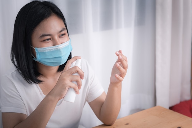 Asian young woman wearing mask and spray alcohol bottle to protect from coronavirus epidemic