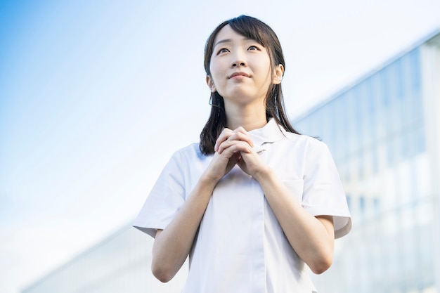기도 포즈에 흰색 코트에 아시아 젊은 여자