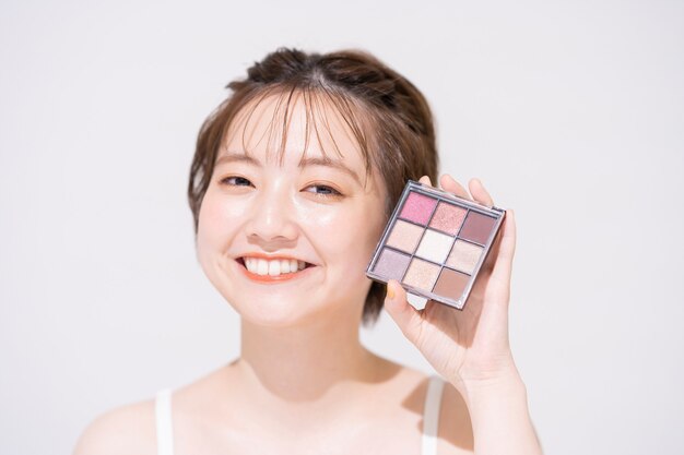 Photo asian young woman with cosmetic items and white background