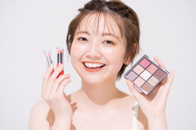 Photo asian young woman with cosmetic items and white background