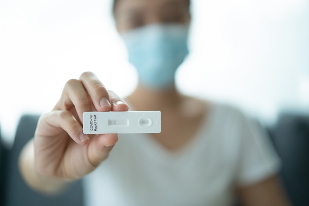 Giovane donna asiatica con maschera facciale protettiva igienica che utilizza il kit di test rapido dell'antigene coronavirus sars 2019-ncov covid-19 - kit di test ag a casa. test rapido dell'antigene covid-19.
