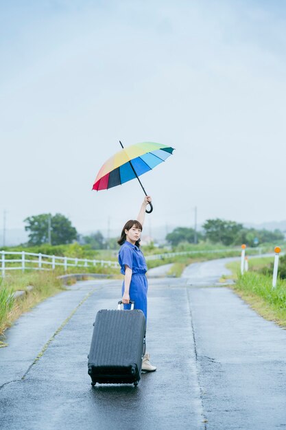 Asian young woman with suitcase and colorful umbrella