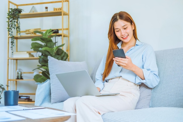 Giovane donna asiatica che lavora da casa usando il computer e bevendo caffè nella sua stanza documenta la finanza e la conferenza online per nuovi progetti