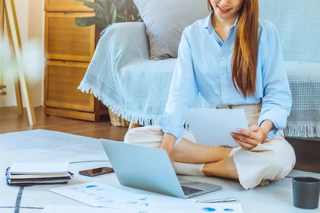 Foto giovane donna asiatica che lavora da casa usando il computer e bevendo caffè nella sua stanza documenta la finanza e la conferenza online per nuovi progetti