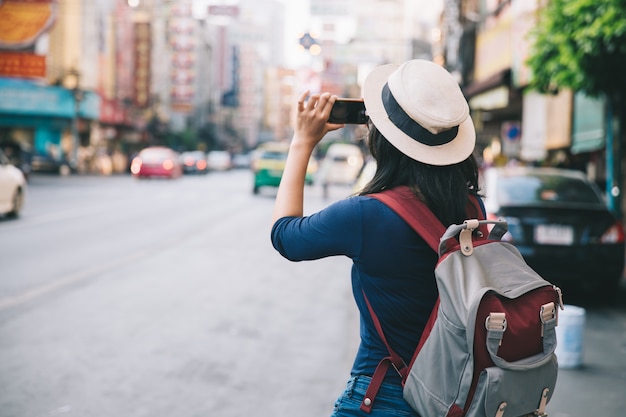 Foto le giovani donne asiatiche prendono la foto con il viaggiatore con zaino e sacco a pelo mobile di telefonata in yaowarat road.