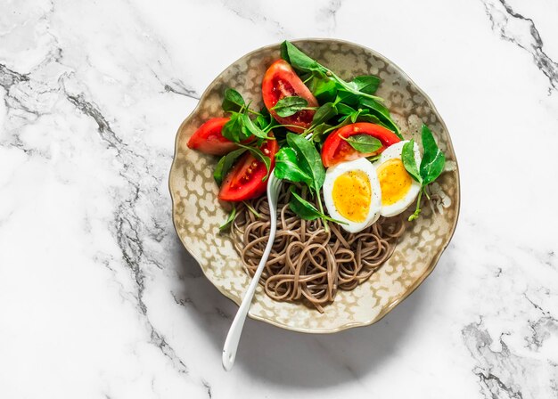 Asianstyle ontbijt boekweit noedels gekookte ei tomaten spinazie salade op een lichte achtergrond bovenaanzicht