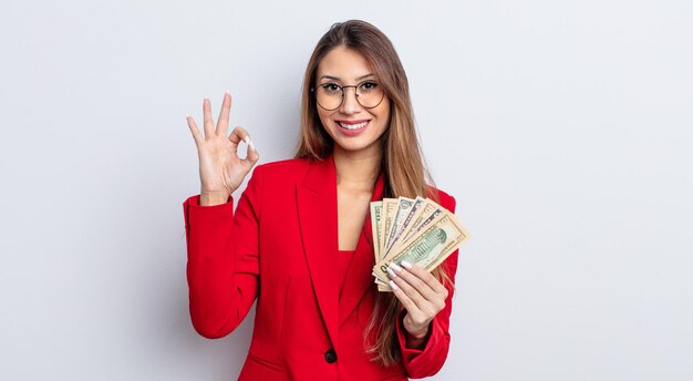 Asiatic pretty woman feeling happy showing approval with okay gesture business and banknotes concept