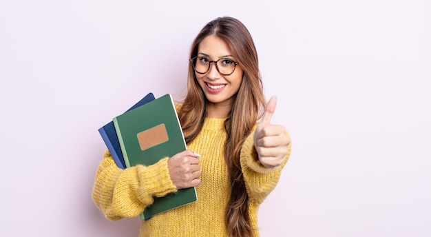 Bella donna asiatica che si sente orgogliosa, sorride positivamente con i pollici in su. concetto di studente