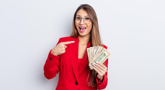 Asiatic pretty woman looking excited and surprised pointing to the side. business and banknotes concept