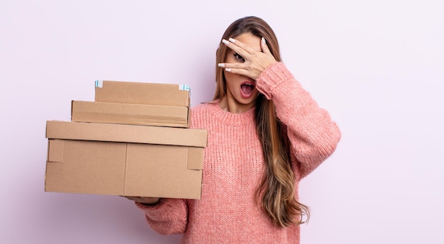 Asiatic pretty woman looking shocked, scared or terrified, covering face with hand. storage boxes concept